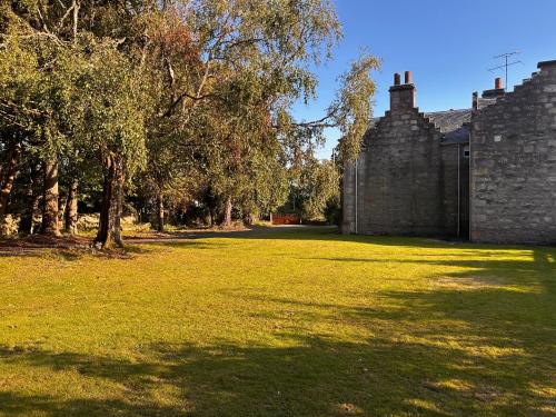 a large yard with trees and a brick building at Clashmore House in Dornoch