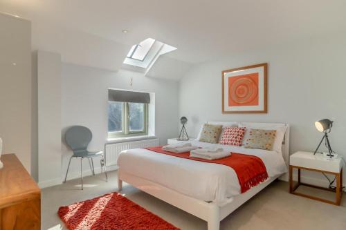 a white bedroom with a bed and a chair at East Barn Cottage in Aldringham