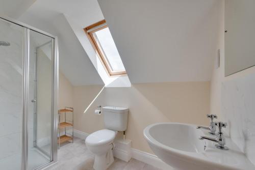 a bathroom with a toilet and a sink and a window at Sailors Rest in Wangford