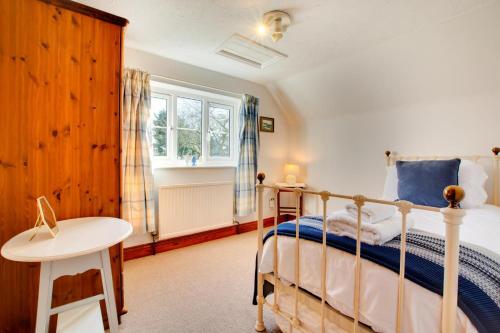 ein Schlafzimmer mit einem Bett und einem Tisch und einem Fenster in der Unterkunft Haven Cottage in South Walsham