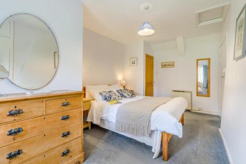 a bedroom with a bed with a mirror and a dresser at 3 Church Street in Reepham