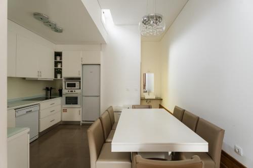 a white kitchen with a white table and chairs at Casa de Cambres - by RowdHouses in Lamego