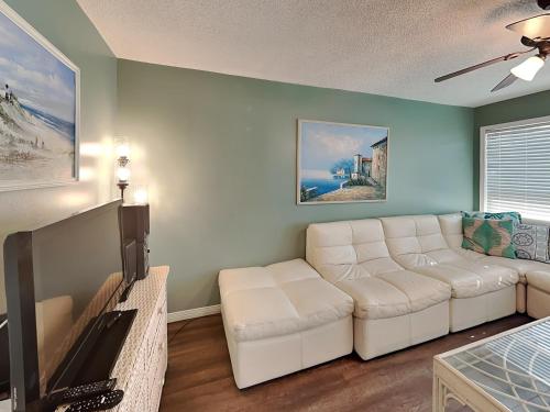 a living room with a white couch and a tv at La Bahia #125 in Pensacola Beach