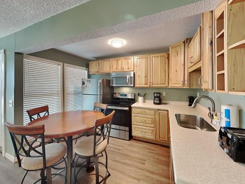 a kitchen with wooden cabinets and a table with chairs at La Bahia #125 in Pensacola Beach