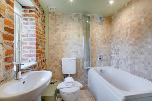 a bathroom with a tub and a toilet and a sink at Crossways Barn in Briston
