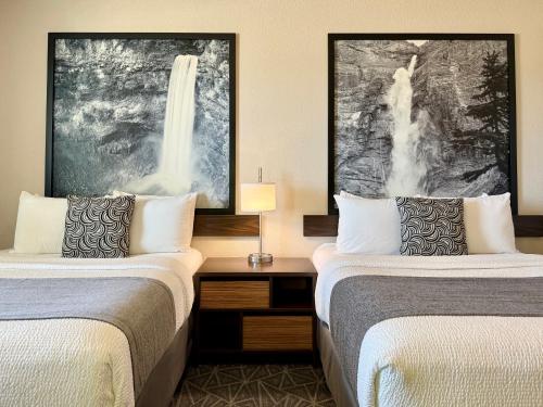 a hotel room with two beds and a desk between them at High Point Inn & Suites Peace River in Peace River