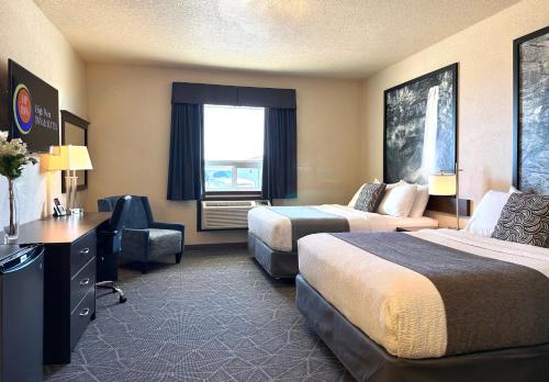a hotel room with two beds and a desk and a chair at High Point Inn & Suites Peace River in Peace River