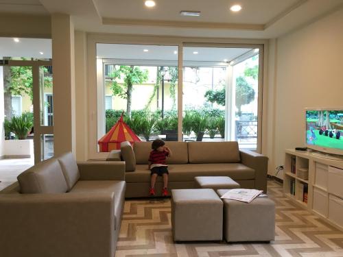 un bambino in piedi su un divano in soggiorno di Hotel Lux a Gabicce Mare
