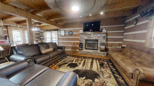 a living room with leather couches and a fireplace at Dogwood Acre cabin in Little Cove