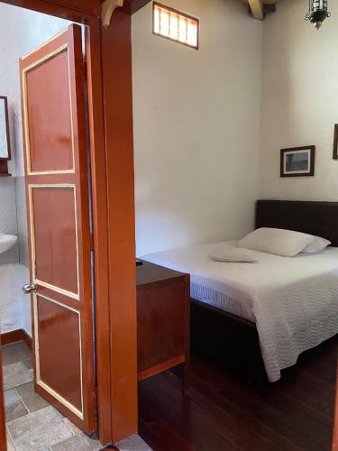 a small bedroom with a bed and a door at Casa Patrimonial Abejorral - CASA GASAMA in Abejorral