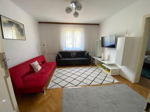 a living room with a red couch and a tv at Eisenerzer Apartments - Radmeisterhaus in Eisenerz