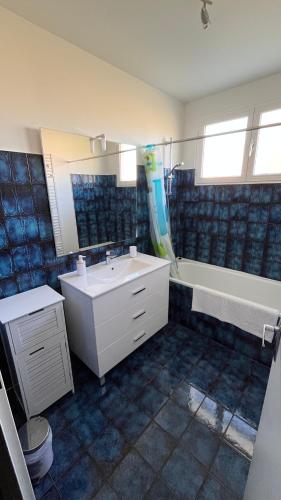 a bathroom with a white sink and a bath tub at La Parenthèse in Longchaumois