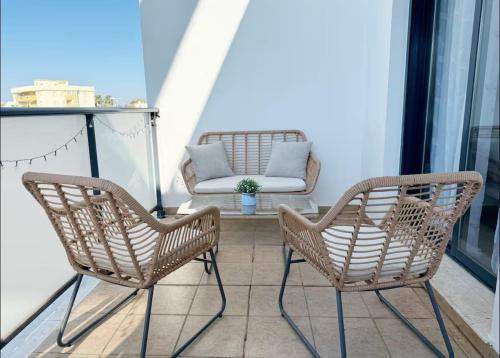 two rattan chairs and a chair on a balcony at Petite Paradise Oliva in Oliva