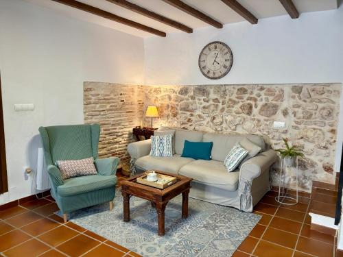 a living room with a couch and two chairs and a clock at MASÍA de SAN JUAN CASA NÚMERO 1 en Castillo con piscina y Aire Acondicionado in Segorbe