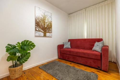 a red couch in a living room with a plant at אלומה- בוטיק בטבע in Sheʼar Yashuv
