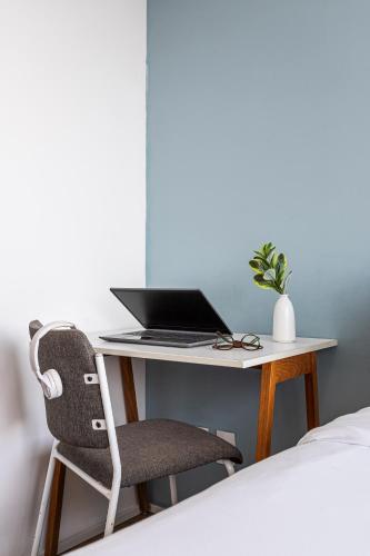 a desk with a laptop and a chair next to a bed at Setin Downtown Praca da Sé by Viva - Prédio completo com piscina perto de estação de metrô no Centro de São Paulo in Sao Paulo