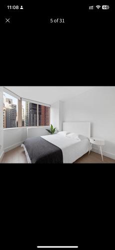 a white bedroom with a bed and a desk at Unique Place in midtown NYC in New York