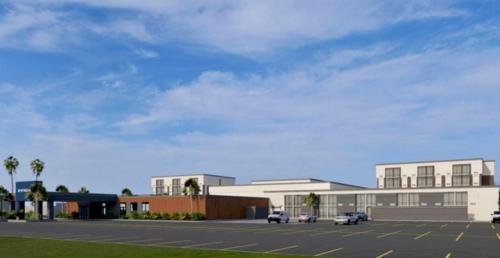 a parking lot with cars parked in front of a building at Wyndham New Orleans Airport & Conference Center in Kenner
