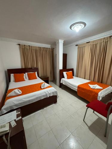 a hotel room with two beds and a chair at Hotel De La Prada in Maicao