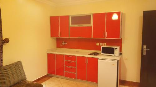 a small kitchen with red cabinets and a microwave at فيا للشقق المخدومة in Al Khobar