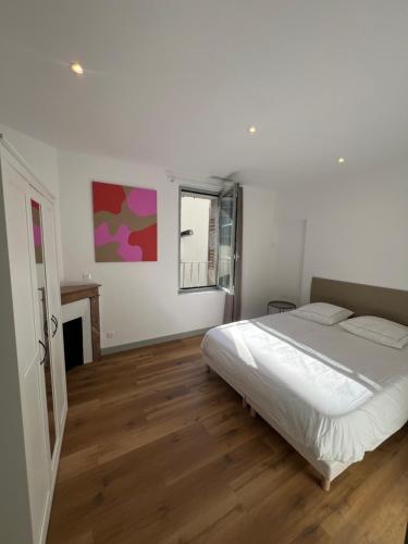 a white bedroom with a bed and a fireplace at La Maison des Filles in Agen