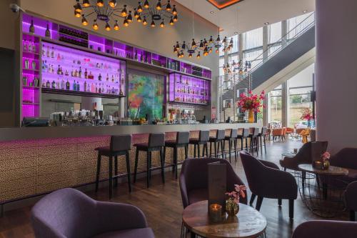 a bar in a restaurant with purple lighting at Leonardo Royal Hotel Amsterdam in Amsterdam