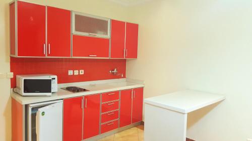 a kitchen with red cabinets and a microwave at فيا للشقق المخدومة in Al Khobar