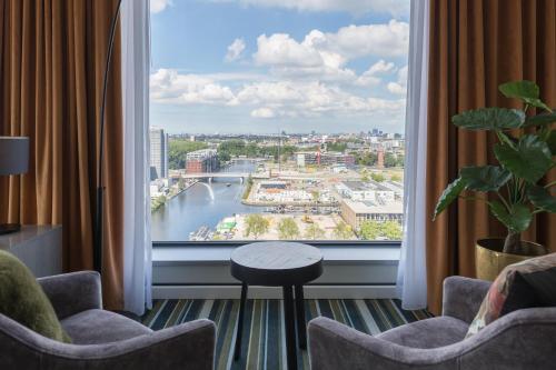 a room with a large window with a view of a river at Leonardo Royal Hotel Amsterdam in Amsterdam