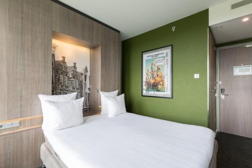 a bedroom with a large white bed with a green wall at Leonardo Hotel Amsterdam Rembrandtpark in Amsterdam