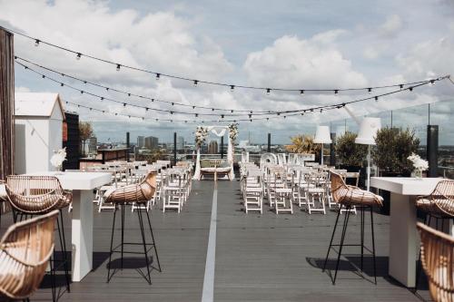 a row of tables and chairs on a rooftop deck at Leonardo Hotel Amsterdam Rembrandtpark in Amsterdam