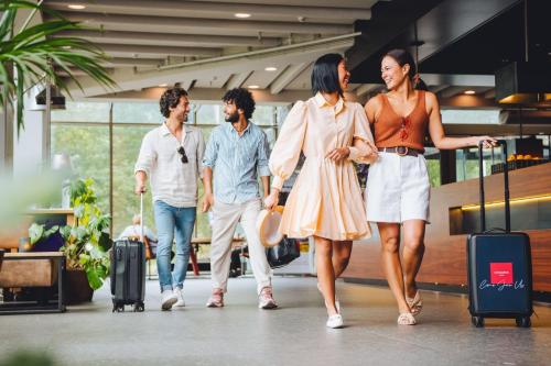a group of people walking with luggage in an airport at Leonardo Hotel Amsterdam Rembrandtpark in Amsterdam