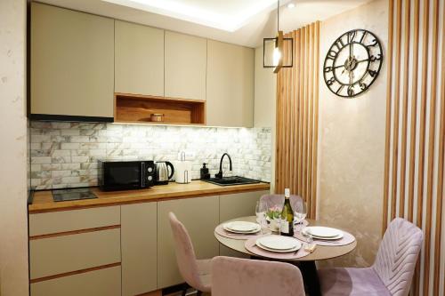 une cuisine avec une table, des chaises et une horloge dans l'établissement Apartman NIKOLINA, à Vrnjačka Banja