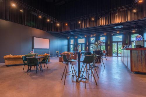 a room with chairs and a bar with a screen at Leonardo Hotel Vinkeveen Amsterdam in Vinkeveen