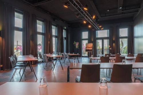 a dining room with tables and chairs and windows at Leonardo Hotel Vinkeveen Amsterdam in Vinkeveen