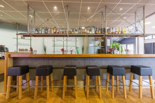 a bar with black stools in a restaurant at Leonardo Hotel Lelystad City Center in Lelystad