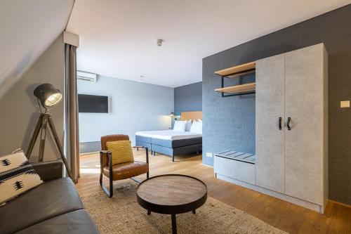 a room with a bed and a couch and a table at Leonardo Hotel Lelystad City Center in Lelystad