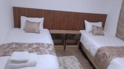 a room with two beds and a wooden table at Guesthouse in Lusaka