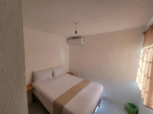 a small bedroom with a white bed and a window at Confort House in Barrio Nuevo