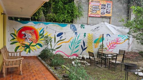 a table and chairs and an umbrella in front of a wall at Apartamentos el viajero in Panajachel
