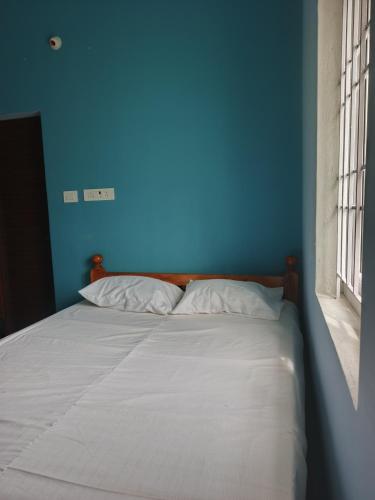 a blue bedroom with a bed with white sheets at Yogi Bhagavan HOME STAY in Tiruvannāmalai