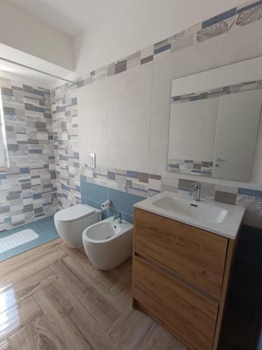 a bathroom with a sink and a toilet and a mirror at Solleone - Appartamento 2B in Paestum