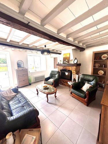 a living room with leather furniture and a fireplace at Grande maison avec tranquillité garantie in Lessay