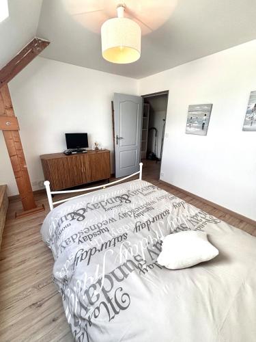 a bedroom with a large white bed and a television at Grande maison avec tranquillité garantie in Lessay