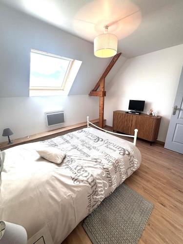 a bedroom with a large white bed with a window at Grande maison avec tranquillité garantie in Lessay