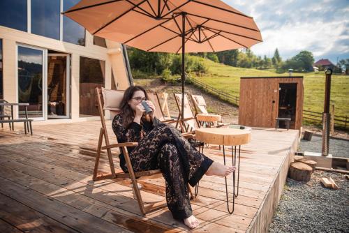 a woman sitting in a chair under an umbrella at Cabana KayLuna in Mătişeşti