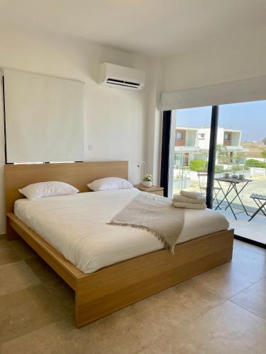 a bedroom with a large bed and a large window at Nadine sea side villas in Larnaca