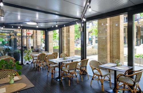 a restaurant with tables and chairs and windows at Leonardo Boutique Hotel Budapest M-Square in Budapest