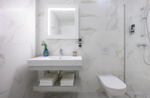 a white bathroom with a sink and a toilet at Leonardo Boutique Hotel Budapest M-Square in Budapest