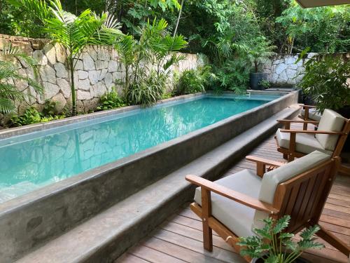 a swimming pool with two chairs and a table at Casa Xunan - Beautiful 1 Bedroom Apartment with pool in Mahahual