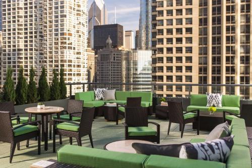 a rooftop patio with green chairs and tables and buildings at The Royal Sonesta Chicago River North in Chicago